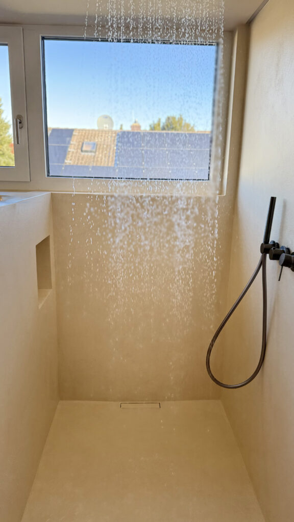 Begehbare Dusche mit fugenlosen Oberflächen und warmer mineralischer Gestaltung