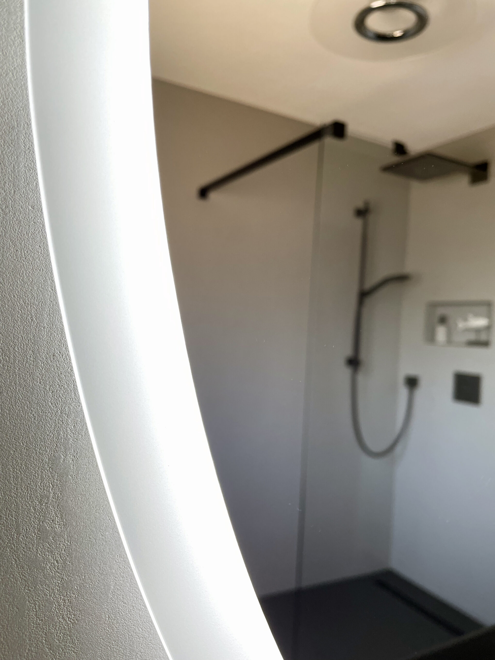 Beleuchteter Spiegel mit Blick auf die fugenlose Dusche